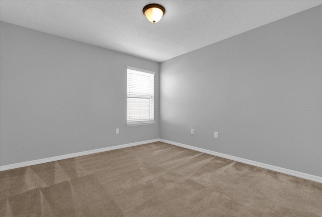 carpeted spare room featuring a textured ceiling and baseboards