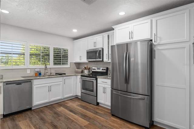 kitchen with dark hardwood / wood-style floors, white cabinetry, sink, and appliances with stainless steel finishes