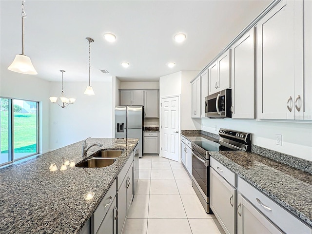 kitchen with pendant lighting, dark stone counters, sink, appliances with stainless steel finishes, and light tile patterned flooring