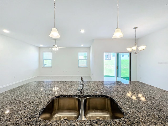 kitchen featuring ceiling fan, plenty of natural light, dark stone counters, and sink