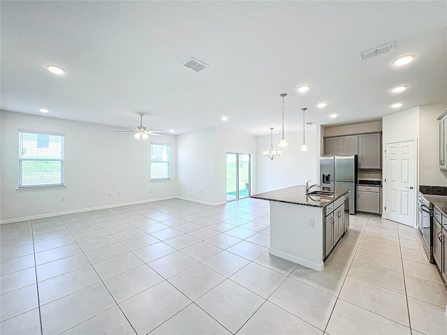 kitchen with a center island with sink, stainless steel fridge, gray cabinetry, and a wealth of natural light