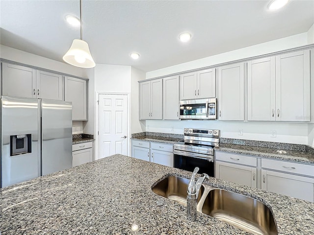 kitchen featuring decorative light fixtures, appliances with stainless steel finishes, and dark stone counters