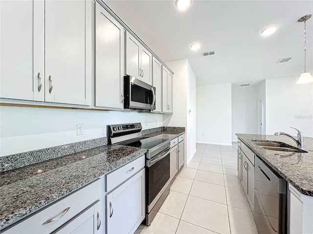 kitchen featuring pendant lighting, sink, dark stone countertops, light tile patterned floors, and appliances with stainless steel finishes