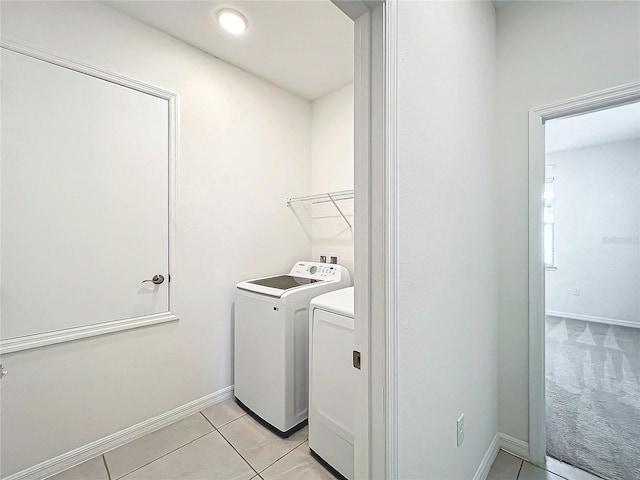 clothes washing area featuring light tile patterned floors and washer and dryer