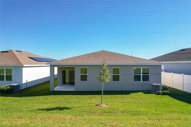 back of property featuring cooling unit and a yard