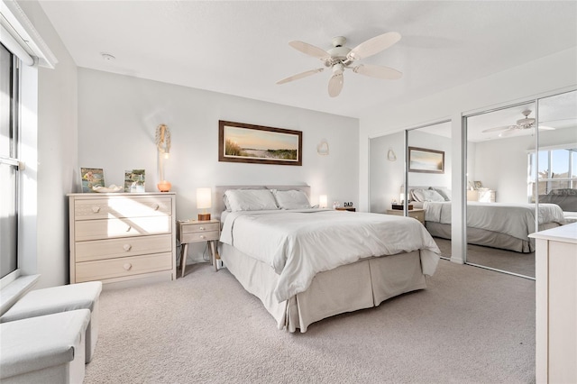 carpeted bedroom with ceiling fan and multiple closets