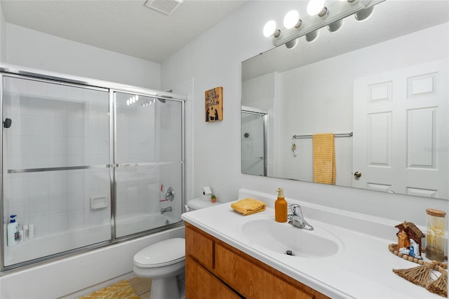 full bathroom featuring tile patterned flooring, enclosed tub / shower combo, a textured ceiling, toilet, and vanity