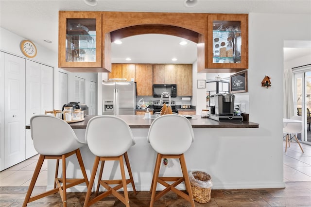 kitchen featuring kitchen peninsula, stainless steel appliances, a breakfast bar area, and light hardwood / wood-style flooring