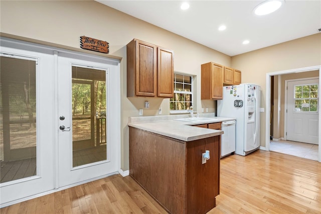 kitchen featuring a healthy amount of sunlight, white appliances, light wood-type flooring, and sink