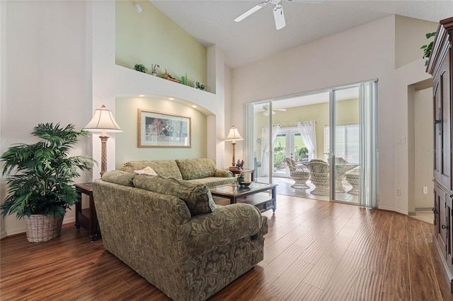 living room with ceiling fan, high vaulted ceiling, and dark wood-type flooring