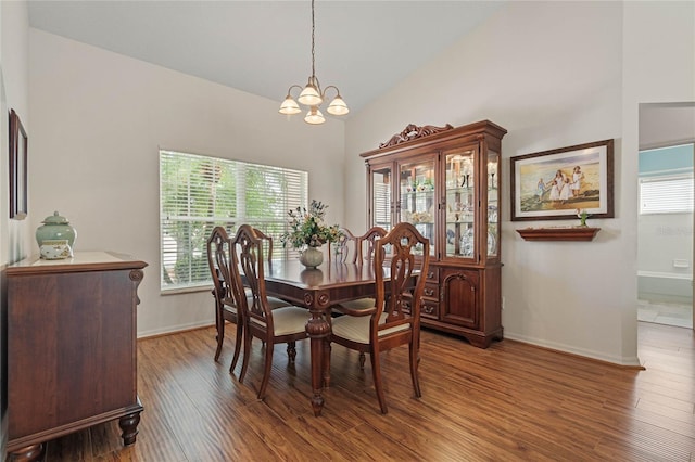 dining space featuring hardwood / wood-style floors, high vaulted ceiling, and an inviting chandelier