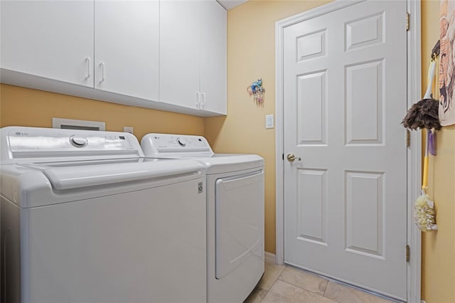 washroom featuring cabinets, light tile patterned flooring, and washer and dryer