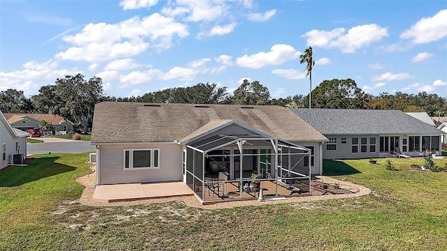 rear view of house with central air condition unit, a patio area, a lanai, and a lawn