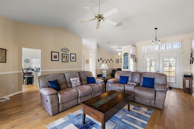 living room featuring french doors, ceiling fan with notable chandelier, light hardwood / wood-style floors, and lofted ceiling