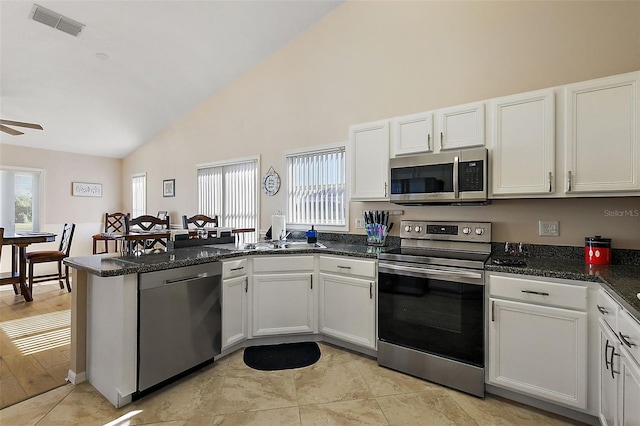 kitchen featuring stainless steel appliances, white cabinetry, and dark stone countertops