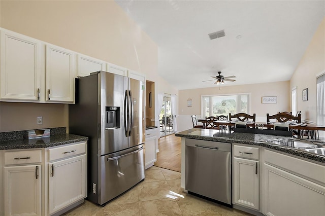 kitchen with white cabinetry, dark stone counters, vaulted ceiling, and appliances with stainless steel finishes