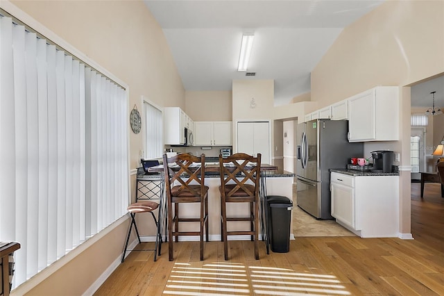 kitchen with a kitchen breakfast bar, light wood-type flooring, and white cabinetry