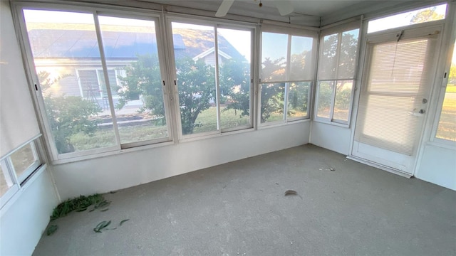 unfurnished sunroom featuring ceiling fan and a wealth of natural light