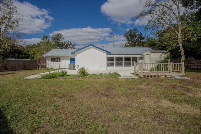 rear view of property featuring a wooden deck, a sunroom, and a yard