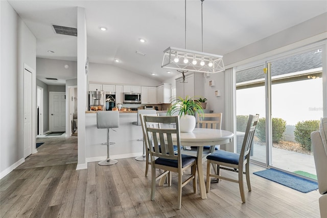 dining room featuring light hardwood / wood-style floors and vaulted ceiling