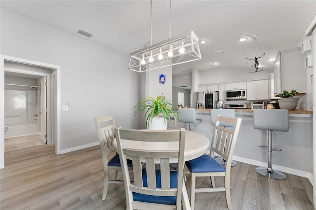 dining space with light hardwood / wood-style flooring and lofted ceiling