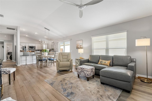 living room with ceiling fan, vaulted ceiling, and light wood-type flooring