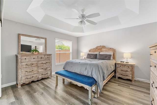 bedroom featuring hardwood / wood-style floors, ceiling fan, and a raised ceiling