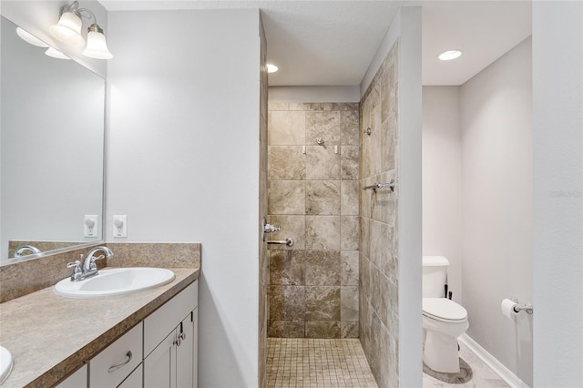 bathroom with vanity, toilet, and a tile shower