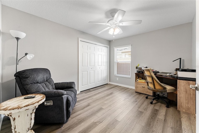 home office with a textured ceiling, light hardwood / wood-style floors, and ceiling fan