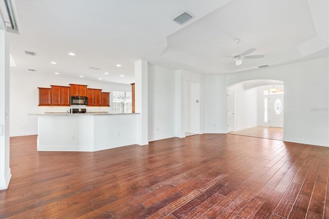 unfurnished living room featuring ceiling fan and dark wood-type flooring