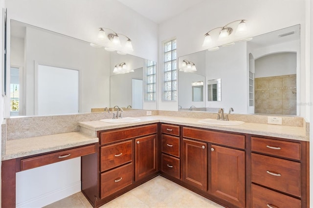 bathroom with a tile shower, vanity, and tile patterned floors