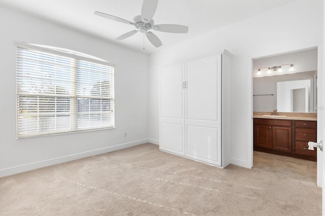 unfurnished bedroom featuring ensuite bath, ceiling fan, sink, and light colored carpet