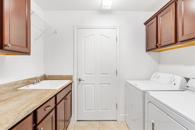 laundry area featuring washing machine and clothes dryer, sink, light tile patterned floors, and cabinets