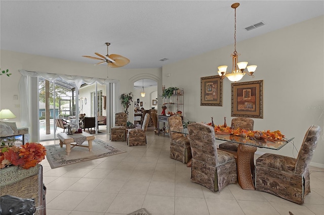 tiled dining space featuring ceiling fan with notable chandelier