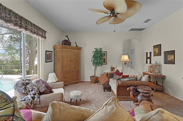 living room featuring carpet flooring, ceiling fan, and a textured ceiling