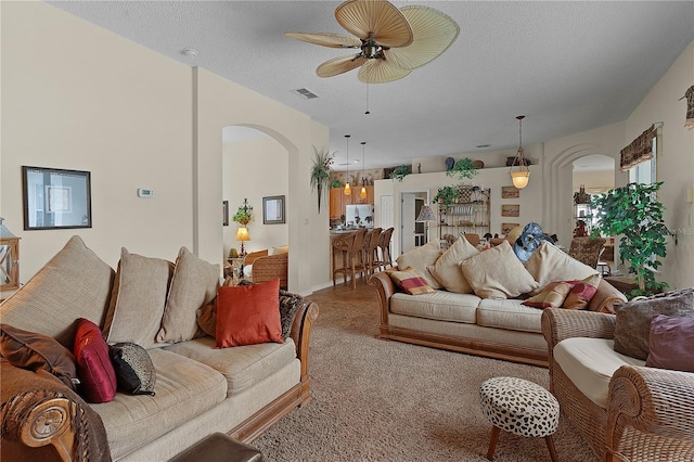 carpeted living room with a textured ceiling and ceiling fan