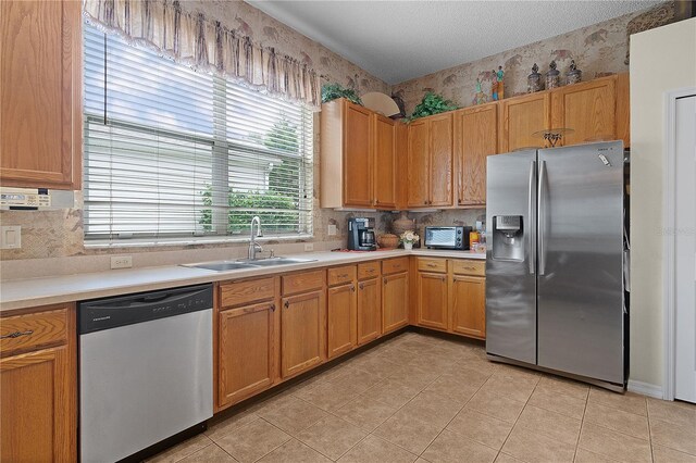 kitchen with sink, light tile patterned floors, stainless steel appliances, and a textured ceiling