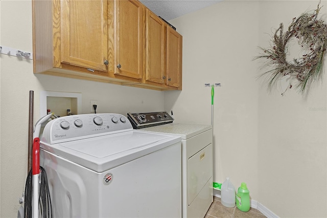 laundry area featuring light tile patterned flooring, cabinets, independent washer and dryer, and a textured ceiling