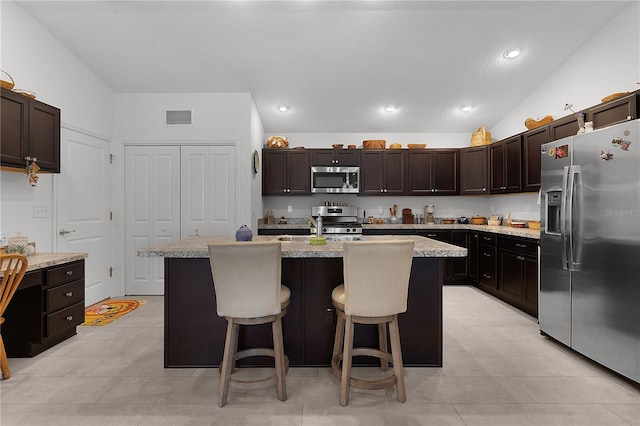 kitchen with stainless steel appliances, lofted ceiling, and an island with sink