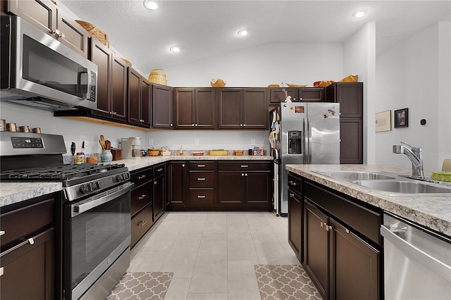 kitchen featuring sink, vaulted ceiling, a textured ceiling, appliances with stainless steel finishes, and dark brown cabinets