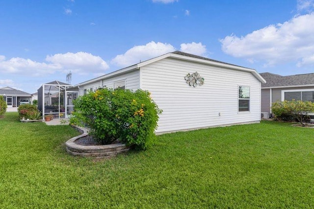 view of side of property featuring a lanai and a lawn