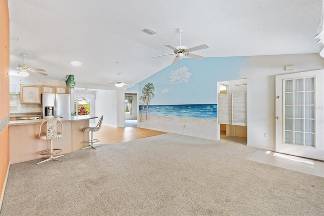 unfurnished living room with light carpet, a textured ceiling, vaulted ceiling, and ceiling fan