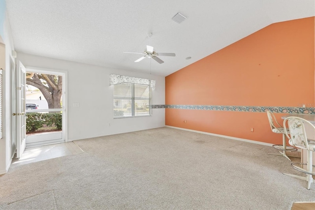 spare room featuring a textured ceiling, light colored carpet, vaulted ceiling, and ceiling fan