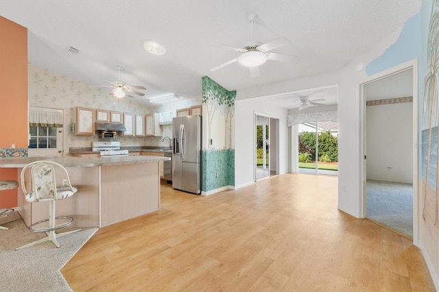 kitchen featuring light hardwood / wood-style floors, stainless steel fridge, kitchen peninsula, and white gas range oven