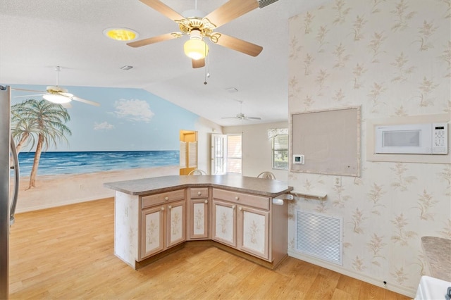 kitchen with light brown cabinets, lofted ceiling, light hardwood / wood-style flooring, ceiling fan, and kitchen peninsula