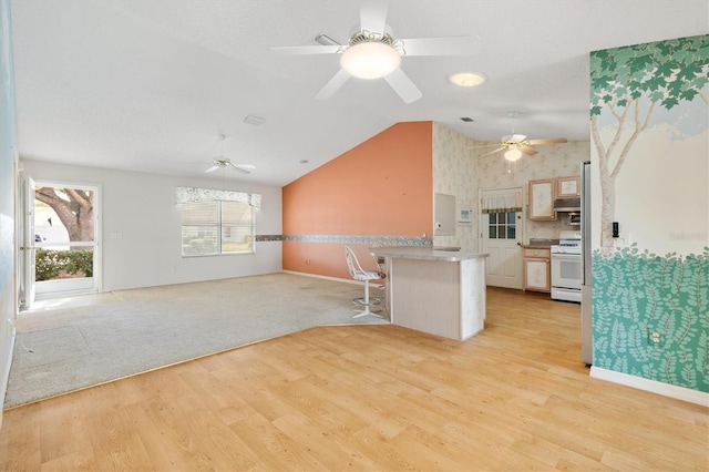 kitchen with kitchen peninsula, light hardwood / wood-style floors, lofted ceiling, a breakfast bar, and white stove