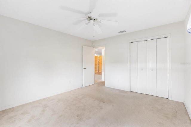 unfurnished bedroom with light carpet, a closet, and ceiling fan