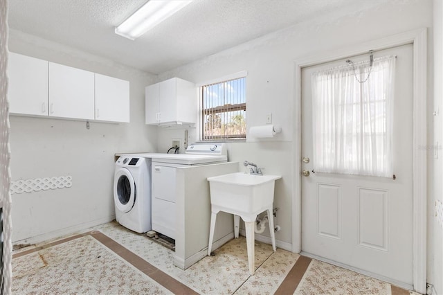 laundry room featuring cabinets, a textured ceiling, and washing machine and dryer