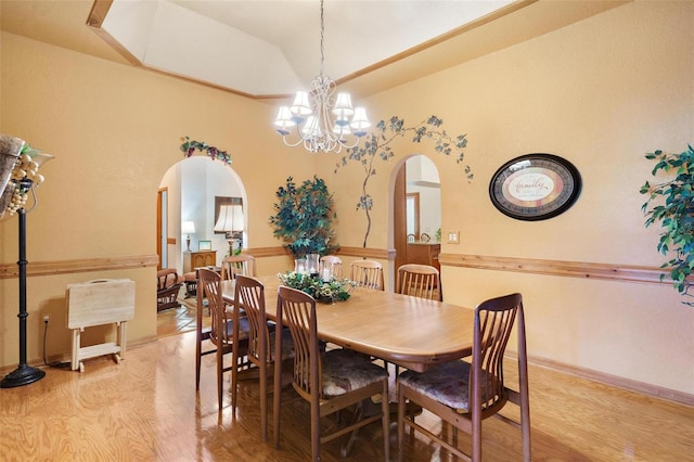 dining area featuring light hardwood / wood-style floors, an inviting chandelier, and lofted ceiling