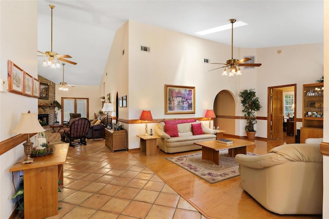 tiled living room featuring ceiling fan, a fireplace, and high vaulted ceiling